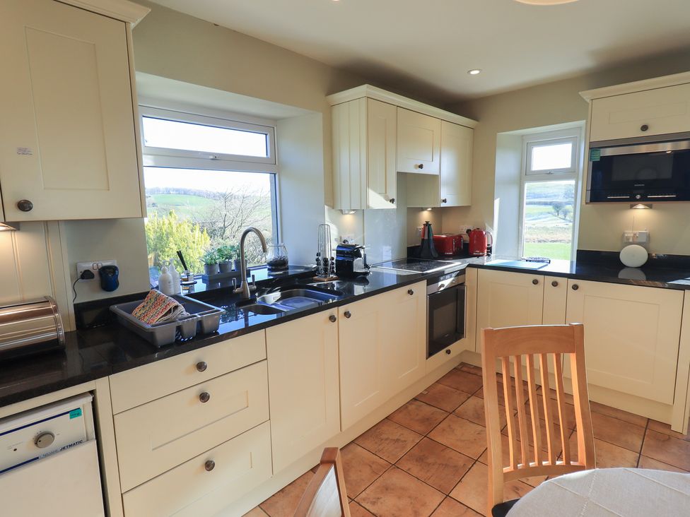 A kitchen with cabinets and appliances at 2 Lupton Hall Cottages in Carnforth
