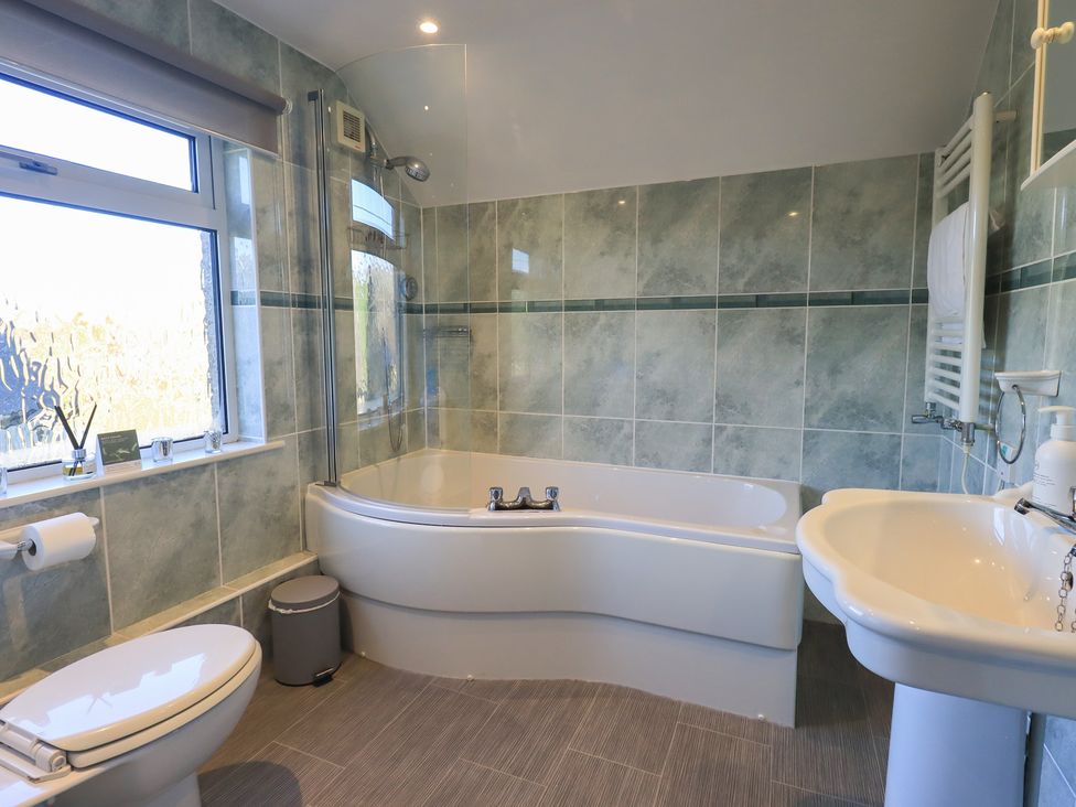 A bathroom with a bathtub, toilet, and sink at 2 Lupton Hall Cottages Carnforth