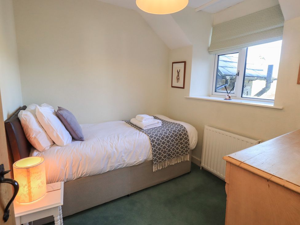 A bedroom with a single bed and a dresser at 2 Lupton Hall Cottages Carnforth