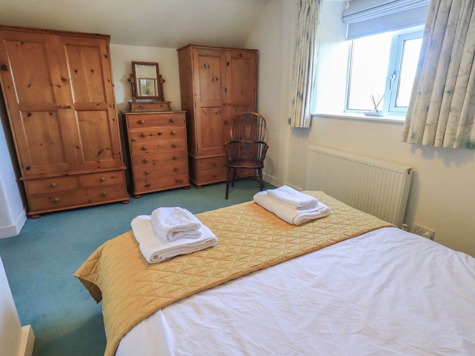 A bedroom with a bed and wooden furniture at 2 Lupton Hall Cottages in Carnforth