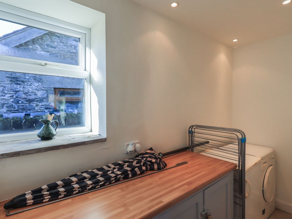 A utility room with a washing machine and drying rack at 2 Lupton Hall Cottages in Carnforth
