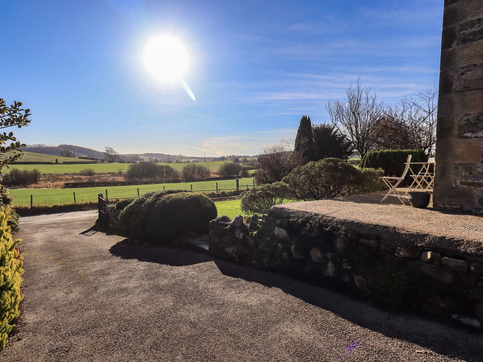A view of a field and chair under sunlight at 2 Lupton Hall Cottages in Carnforth