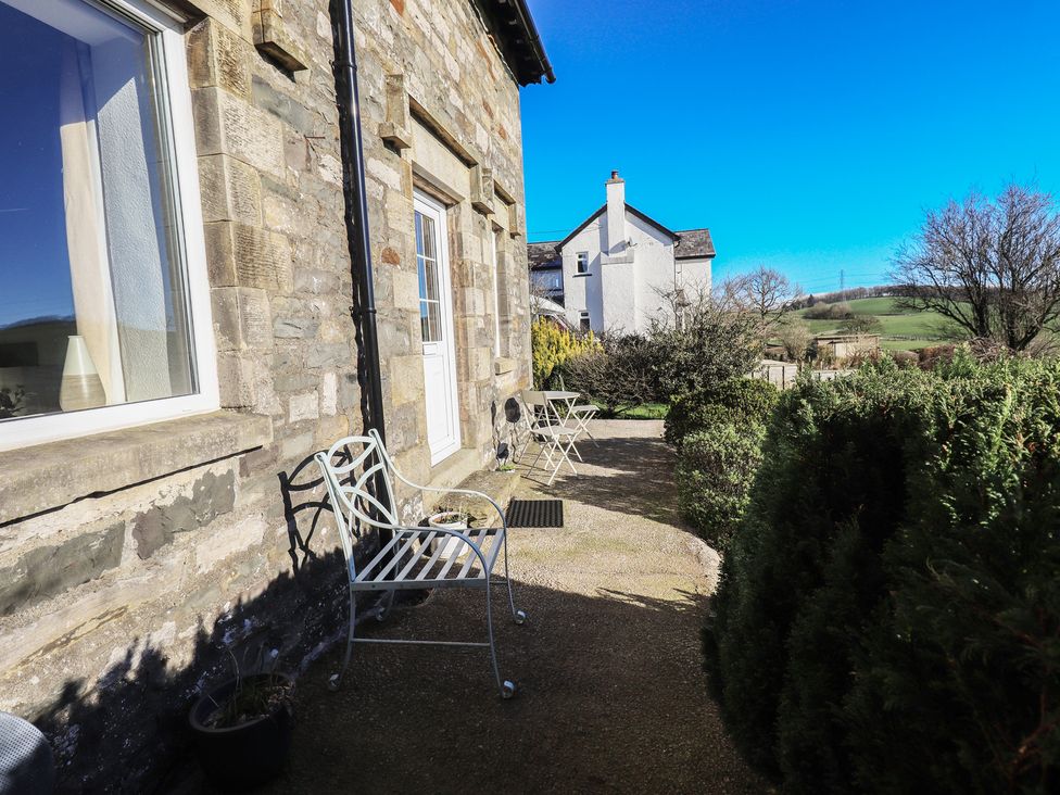 An outdoor area with chairs and a table at 2 Lupton Hall Cottages Carnforth