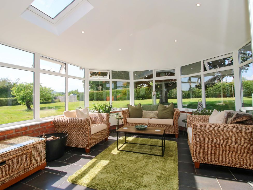 A conservatory with a sofa and coffee table at Fron-Haul Near Llansantffraidd-Ym-Mechain
