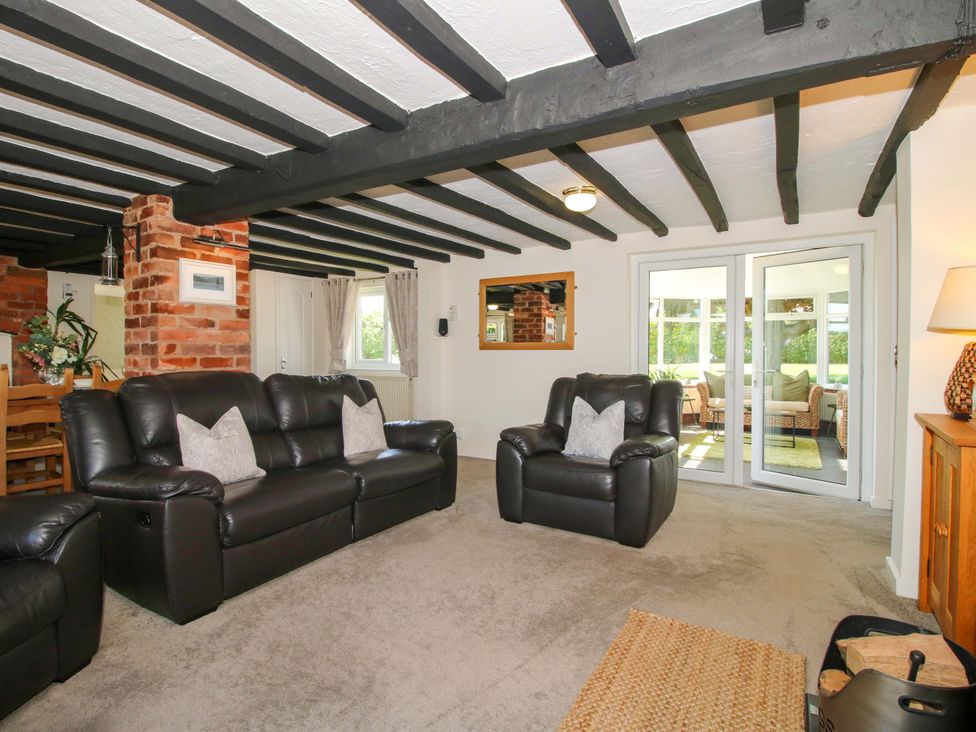 A living room with a sofa and armchair at Fron-Haul near Llansantffraidd-Ym-Mechain