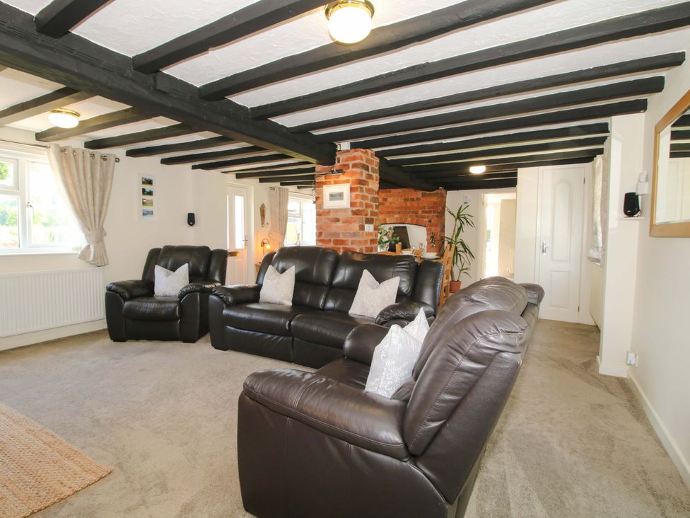 A living room with sofas and a brick wall at Fron-Haul near Llansantffraidd-Ym-Mechain