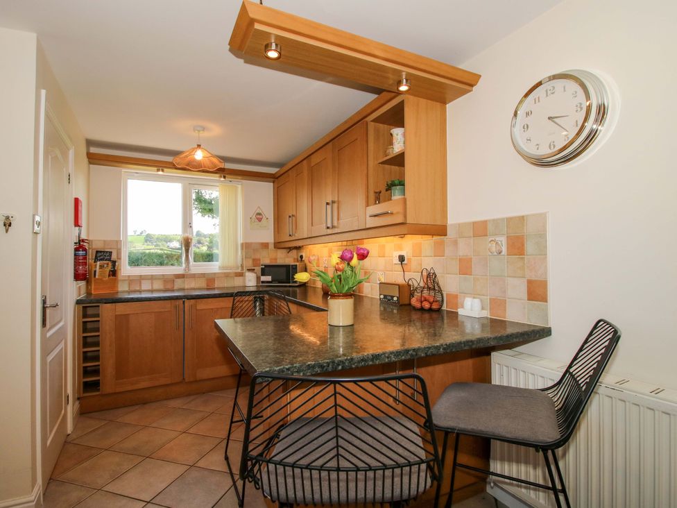 A kitchen with wooden cabinets and a countertop at Fron-Haul Near Llansantffraidd-Ym-Mechain
