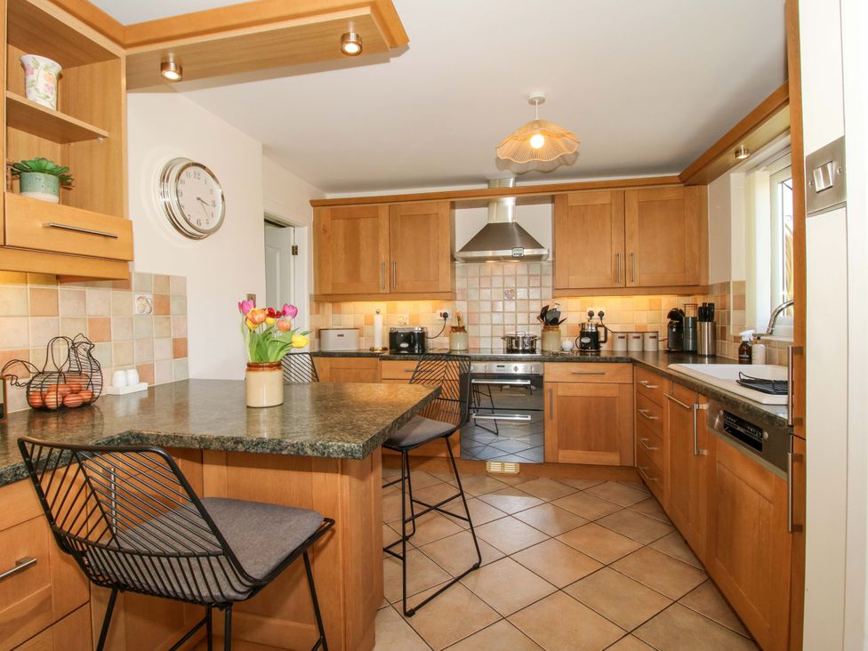 A kitchen with wood cabinets and stainless steel appliances at Fron-Haul Near Llansantffraidd-Ym-Mechain