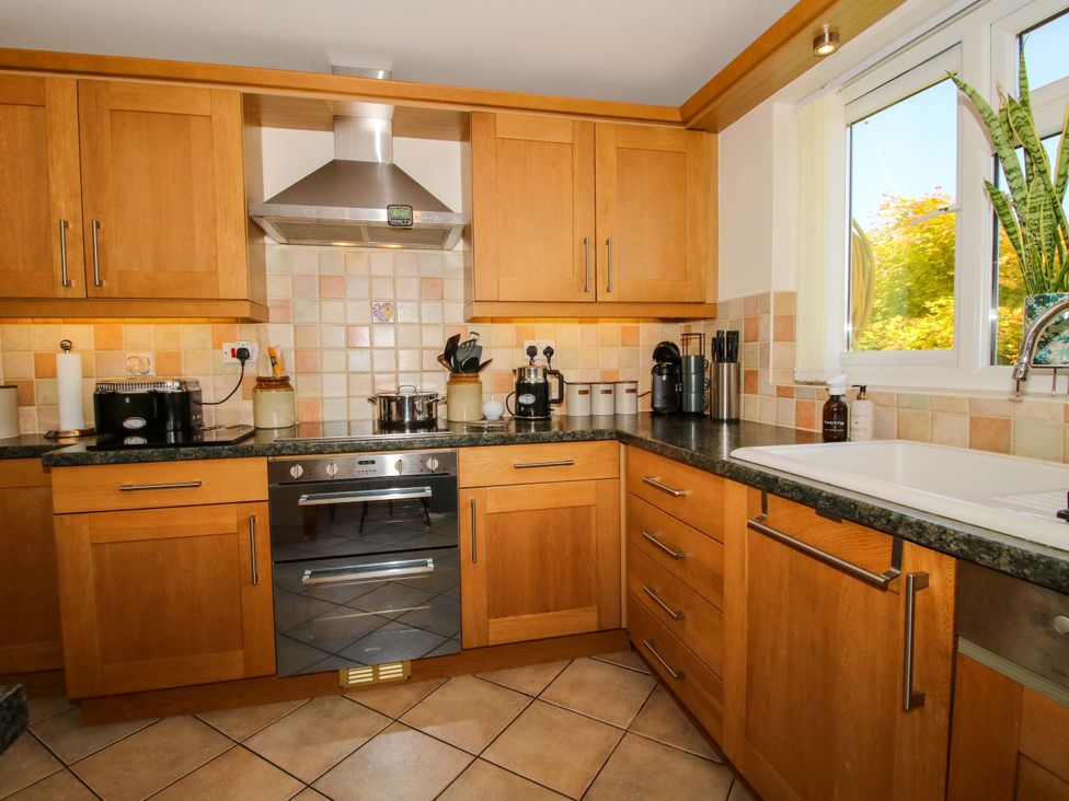 A kitchen with cabinets, a stove, and a sink at Fron-Haul near Llansantffraidd-Ym-Mechain