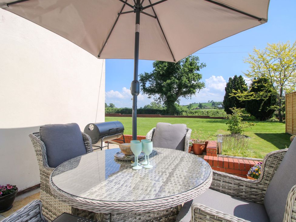A garden seating area with a table and chairs at Fron-Haul Near Llansantffraidd-Ym-Mechain