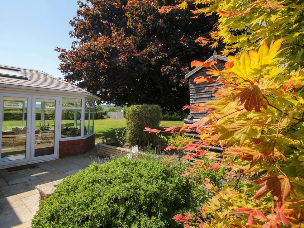 A conservatory and garden area with trees at Fron-Haul Near Llansantffraidd-Ym-Mechain