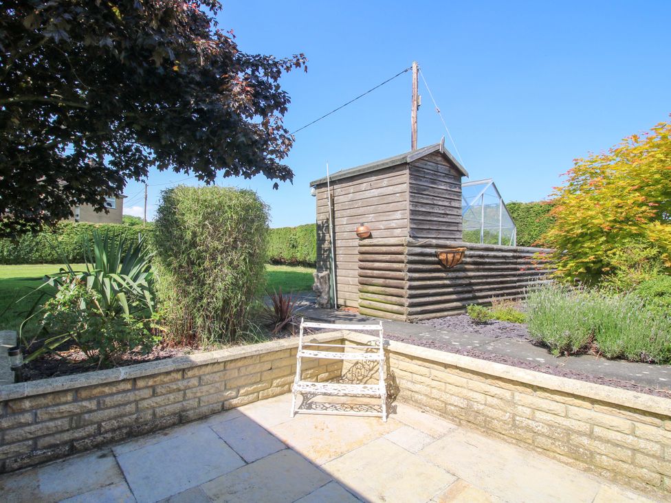 A garden with a wooden shed and plants at Fron-Haul Near Llansantffraidd-Ym-Mechain