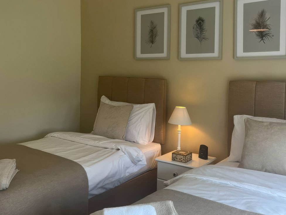 A bedroom with two beds and a nightstand at Fron-Haul near Llansantffraid-Ym-Mechain