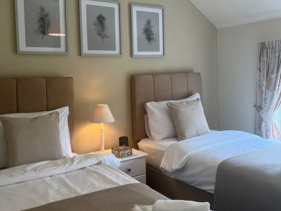 A bedroom with two beds and artwork on the wall at Fron-Haul Near Llansantffraid-Ym-Mechain