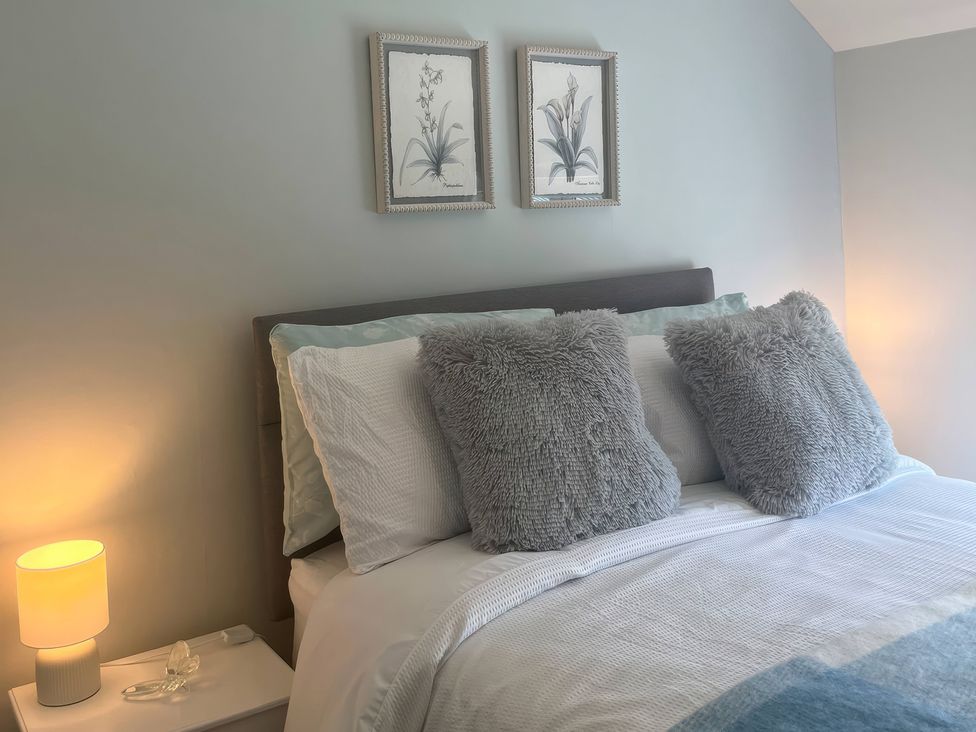 A bedroom with a bed and nightstand at Fron-Haul near Llansantffraid-Ym-Mechain