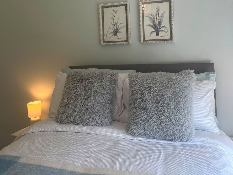 A bedroom with a bed and decorative pillows at Fron-Haul near Llansantffraid-Ym-Mechain