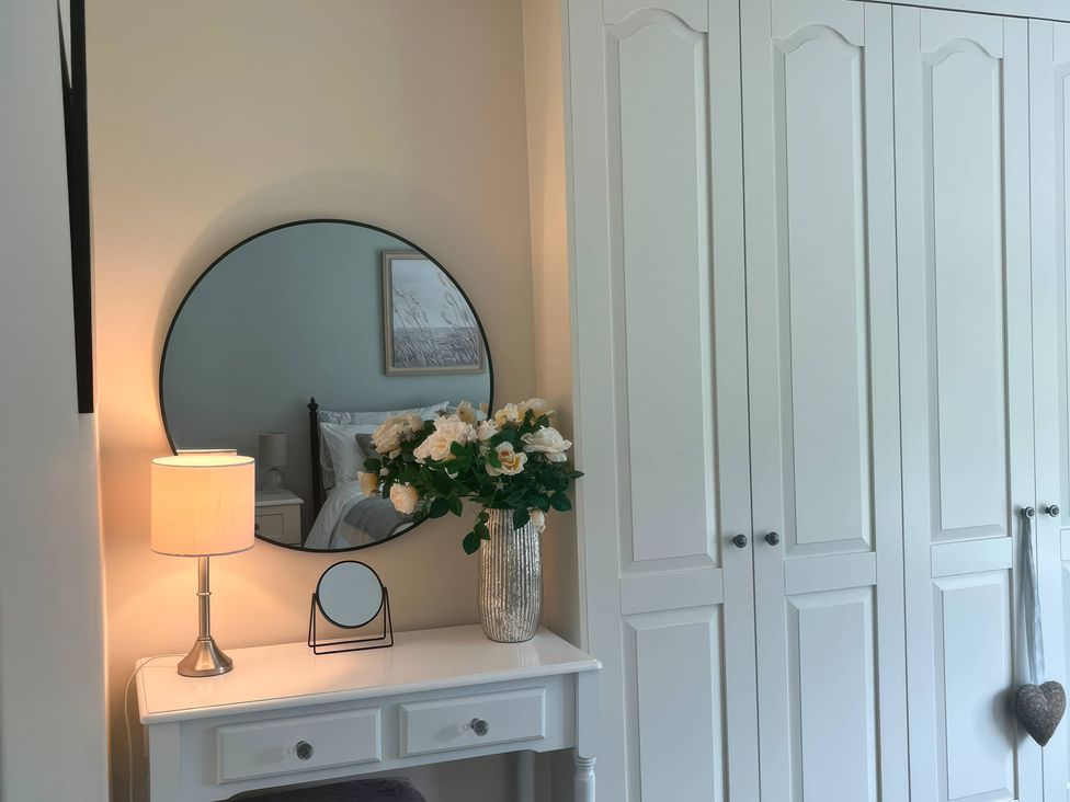 A bedroom with a mirror and flowers on a table at Fron-Haul Near Llansantffraid-Ym-Mechain