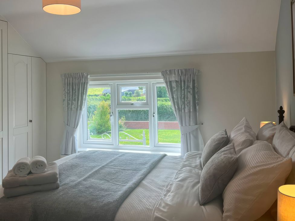A bedroom with a bed and window at Fron-Haul Near Llansantffraid-Ym-Mechain