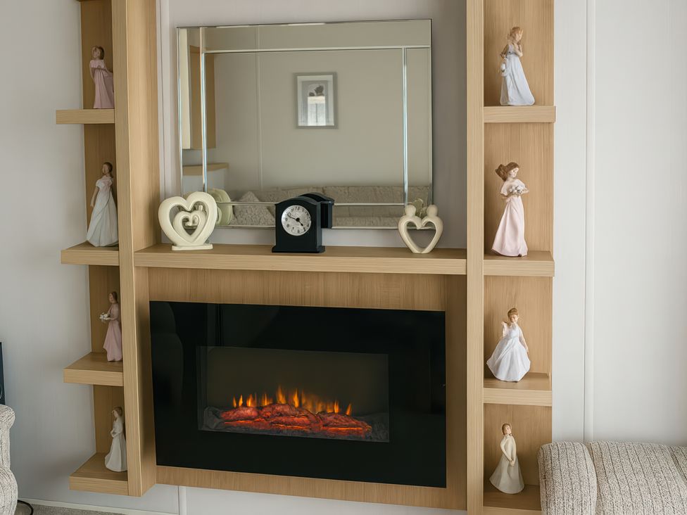 A living room with a fireplace and decorative items at Freshwater Beach Holiday Park - Holiday Accommodation 17116 in Burton Bradstock near Bridport