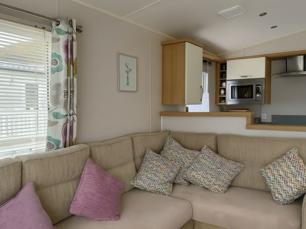 A living room with a sofa and kitchen unit at Freshwater Beach Holiday Park - Holiday Accommodation 17116 in Burton Bradstock near Bridport