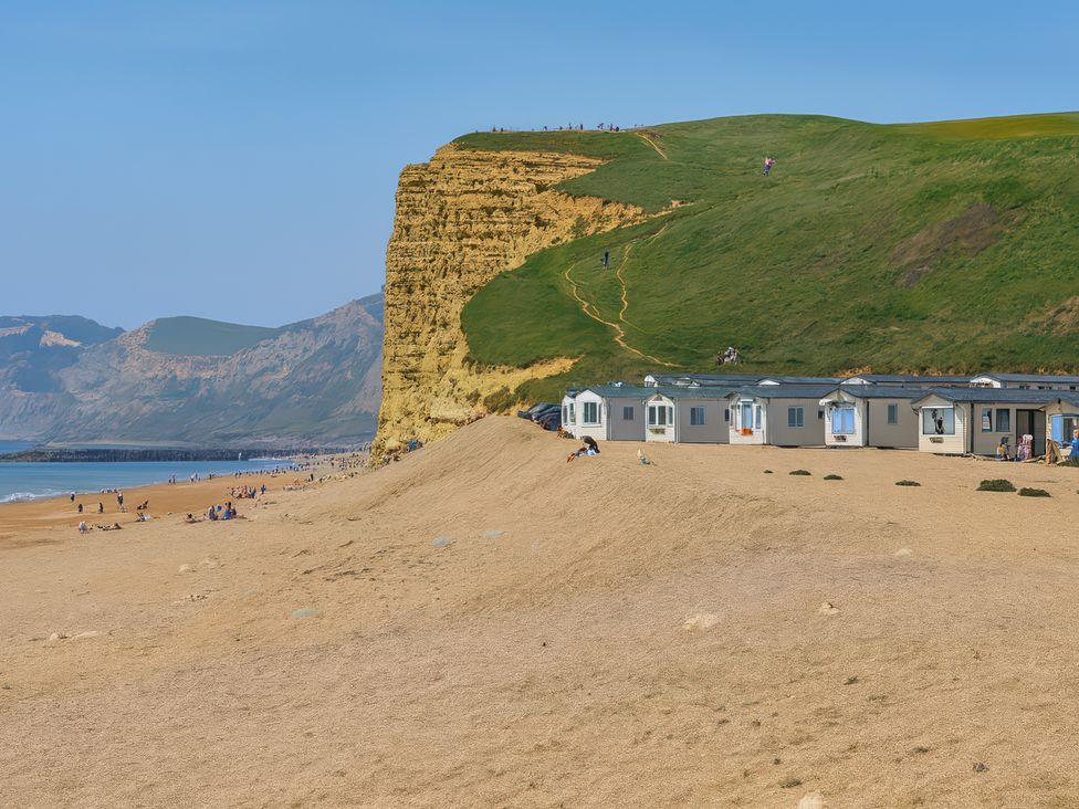 a beach along a coastline with cliffs and holiday accommodations at Freshwater Beach Holiday Park - Holiday Accommodation 17116 Burton Bradstock near Bridport