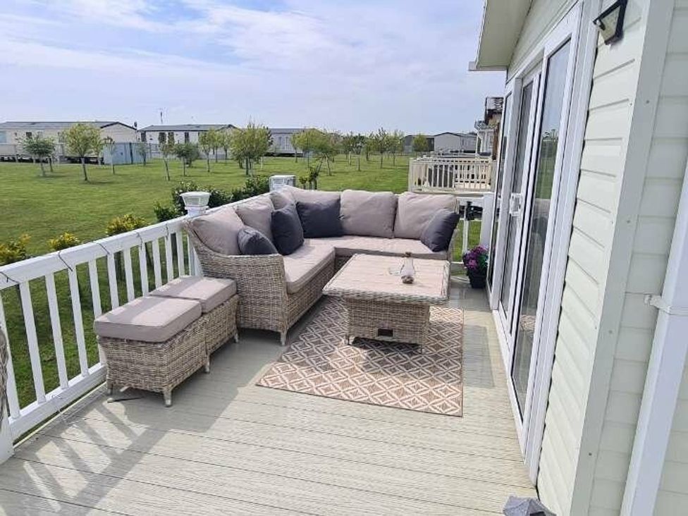 a seating area with a sectional sofa and coffee table on a deck at Golden Anchor Holiday Park - Holiday Accommodation 17383 in Skegness