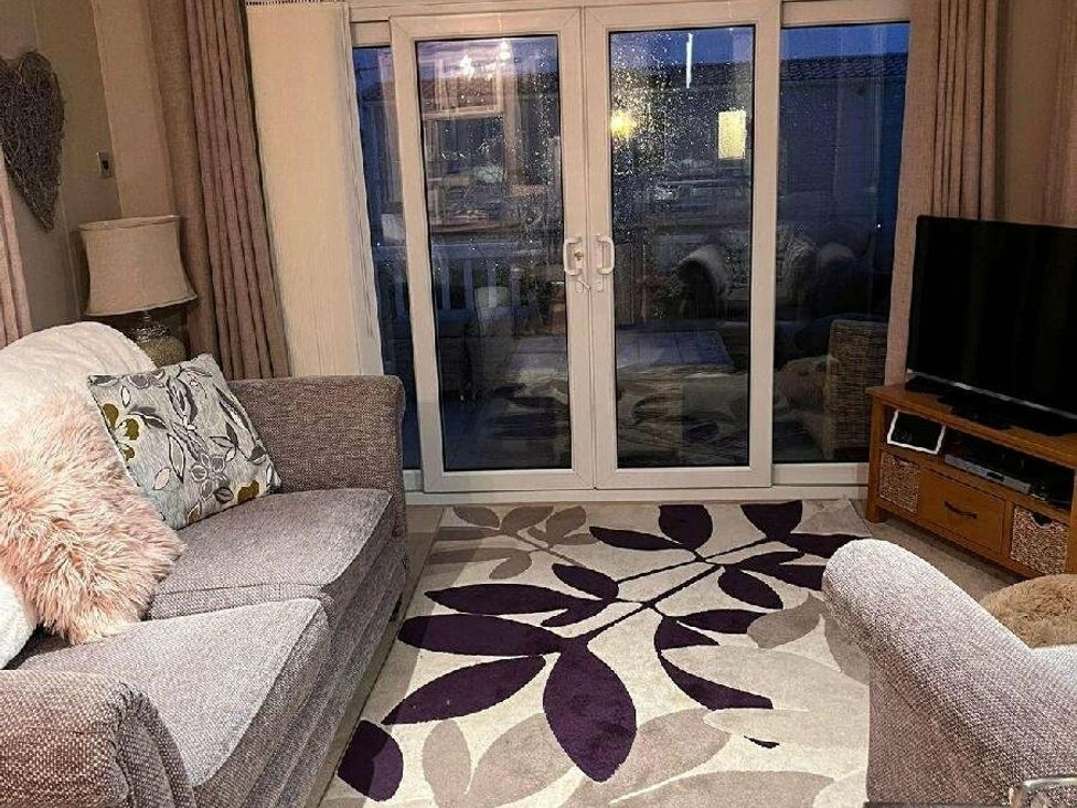 a living room with a gray sofa and TV at Golden Anchor Holiday Park - Holiday Accommodation 17383 in Skegness