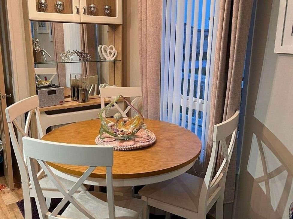 a dining area with a round wooden table and four white chairs at Golden Anchor Holiday Park - Holiday Accommodation 17383, Skegness