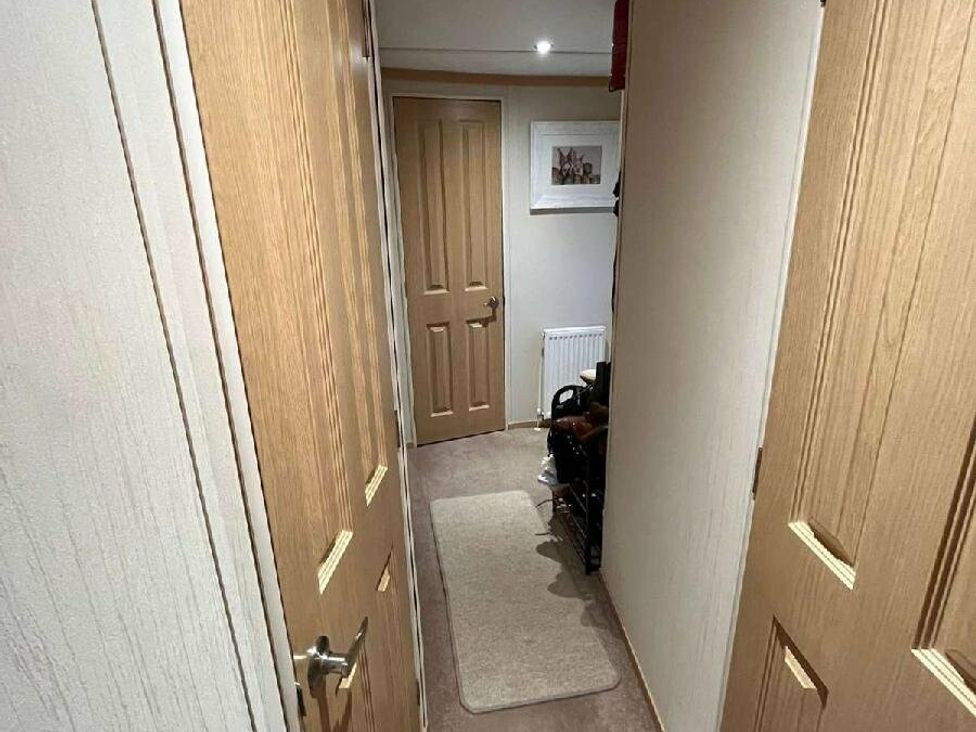 a hallway with two wooden doors and a radiator at Golden Anchor Holiday Park - Holiday Accommodation 17383 in Skegness