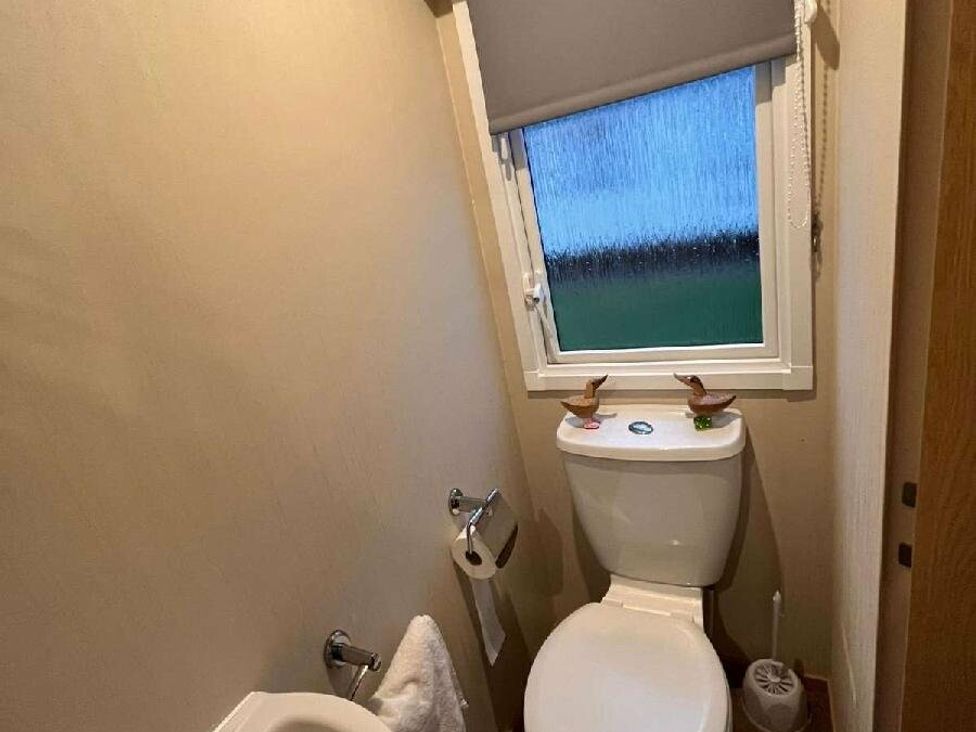 a bathroom with a toilet and a small window at Golden Anchor Holiday Park - Holiday Accommodation 17383 in Skegness