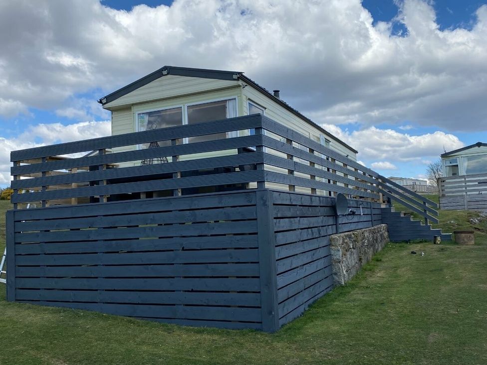 a holiday cabin on grass with a deck and steps at Three Lochs Holiday Park - Holiday Accommodation 17424 Stranraer