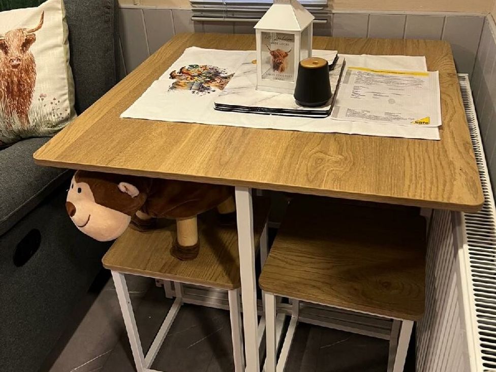 a wooden dining table with two stools, a lantern, and a decorative table runner at Three Lochs Holiday Park - Holiday Accommodation 17424 in Stranraer