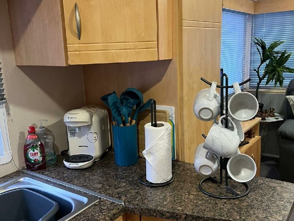 a kitchen counter with utensils, a coffee maker, paper towels, and a mug holder at Three Lochs Holiday Park - Holiday Accommodation 17424 in Stranraer