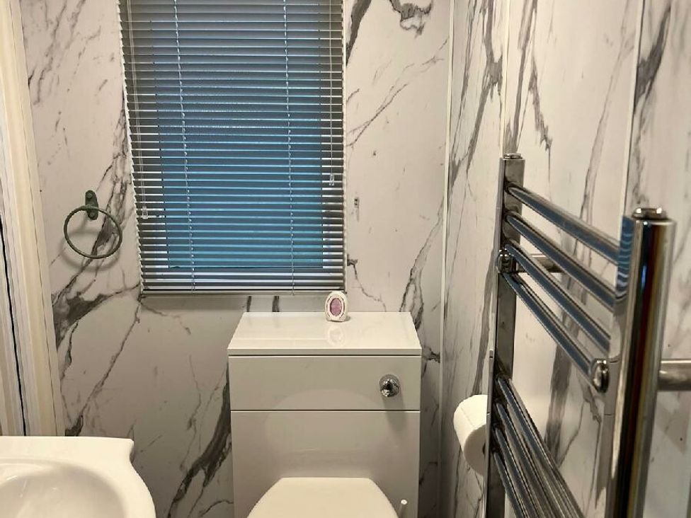 a bathroom with marble wall tiles and a white toilet at Three Lochs Holiday Park - Holiday Accommodation 17424 in Stranraer