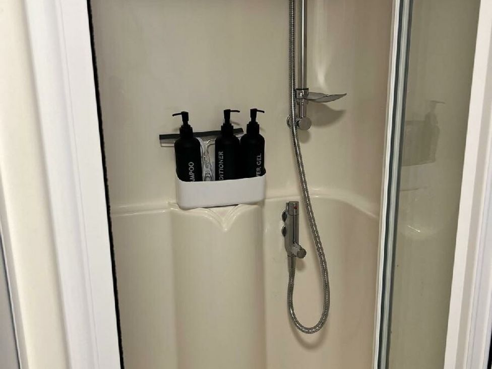 a shower stall with three bottles of liquid soap in a caddy at Three Lochs Holiday Park - Holiday Accommodation 17424 in Stranraer