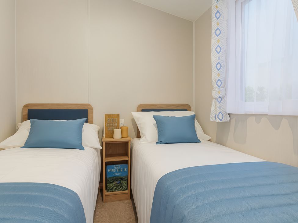 A bedroom with two beds and a bedside table at Marton Mere Holiday Village - Holiday Accommodation 17890, Blackpool
