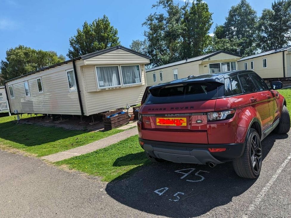 a parked red SUV next to a mobile home in a recreational area at Butlins Minehead - Holiday Accommodation 18045, Minehead