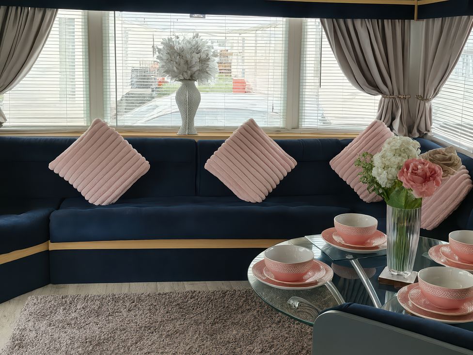 A living room with a sofa, table, and decorative flowers at Millers Cottage Caravan Park - Holiday Accommodation 18845, Towyn, Abergele