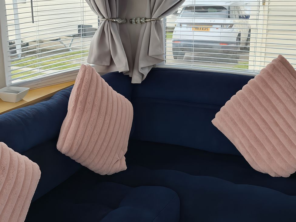 A living room with a couch and pillows at Millers Cottage Caravan Park - Holiday Accommodation 18845 Towyn, Abergele