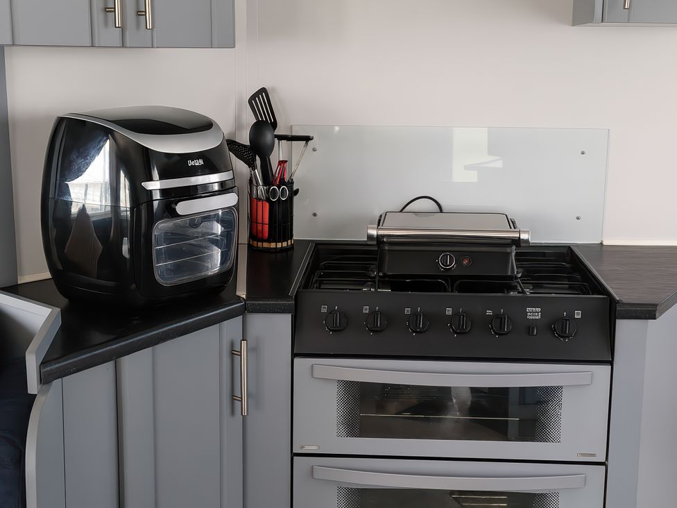 A kitchen with an air fryer and a gas stove at Millers Cottage Caravan Park - Holiday Accommodation 18845, Towyn, Abergele