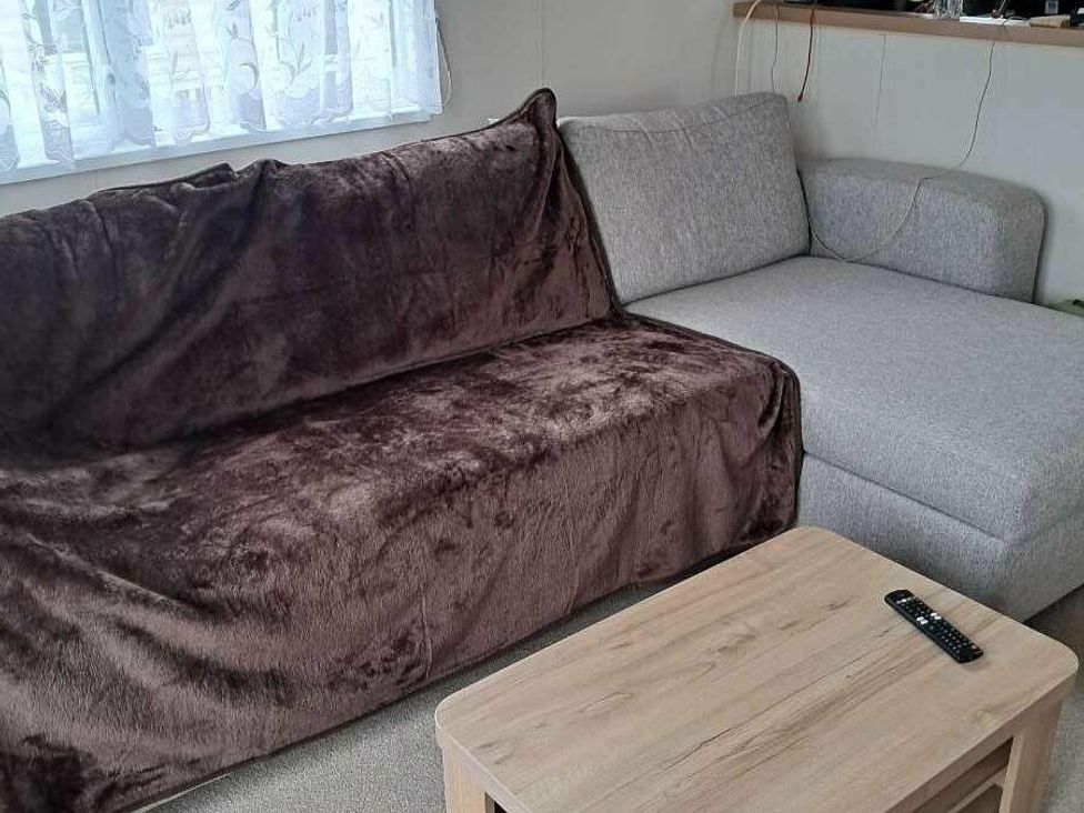 a living room with a brown blanket on a couch and a grey sectional sofa at Golden Sands Holiday Park - Holiday Accommodation 18951, Dawlish