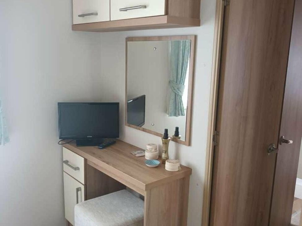 a desk with a TV and mirror in a room at Golden Sands Holiday Park - Holiday Accommodation 18951, Dawlish