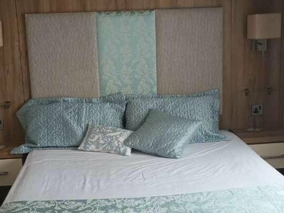 a bed with decorative pillows in a room at Golden Sands Holiday Park - Holiday Accommodation 18951, Dawlish