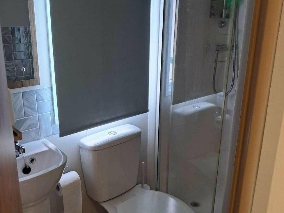 a small bathroom with a shower, toilet, and sink at Golden Sands Holiday Park - Holiday Accommodation 18951, Dawlish