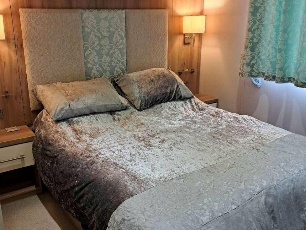 a bedroom with a large bed and bedside lamps at Golden Sands Holiday Park - Holiday Accommodation 18951, Dawlish