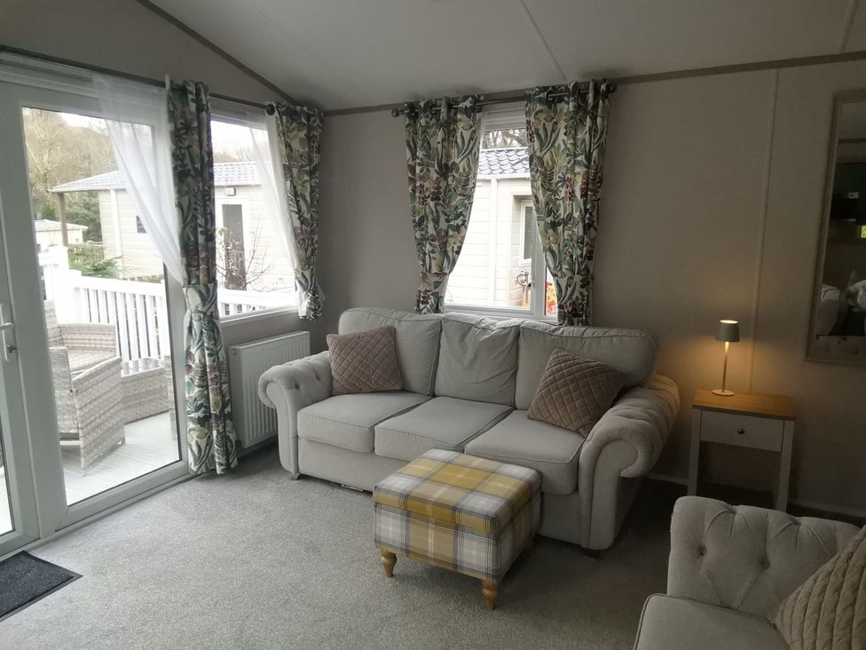 A snug with a sofa and footstool at Aberdunant Hall Holiday Park - Holiday Accommodation 19035, Porthmadog