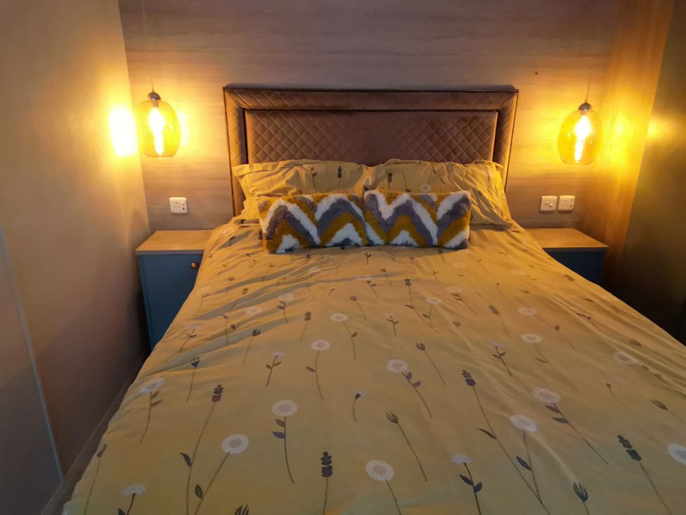 A bed with yellow bedding and decorative pillows at Aberdunant Hall Holiday Park - Holiday Accommodation 19035, Porthmadog