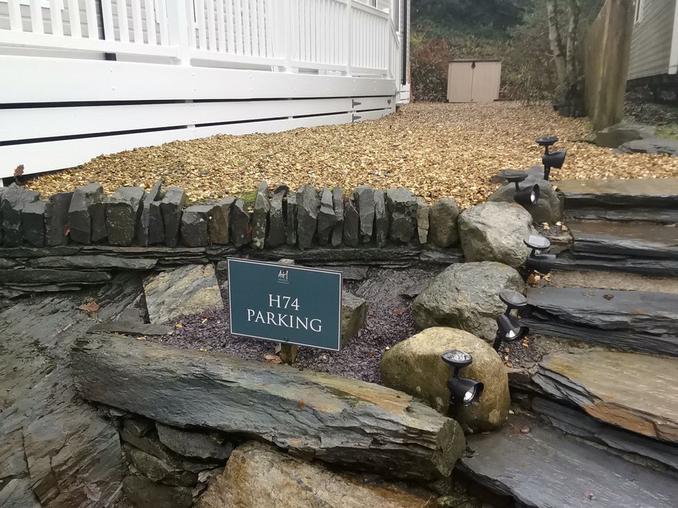 A parking area with a sign and stone steps at Aberdunant Hall Holiday Park - Holiday Accommodation 19035 Porthmadog