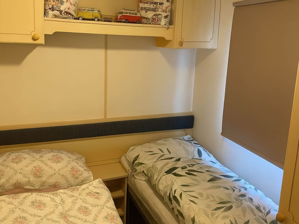 A bedroom with two beds and a shelf of toy cars at Brynowen Holiday Park - Holiday Accommodation 19041 in Borth Mis Wales