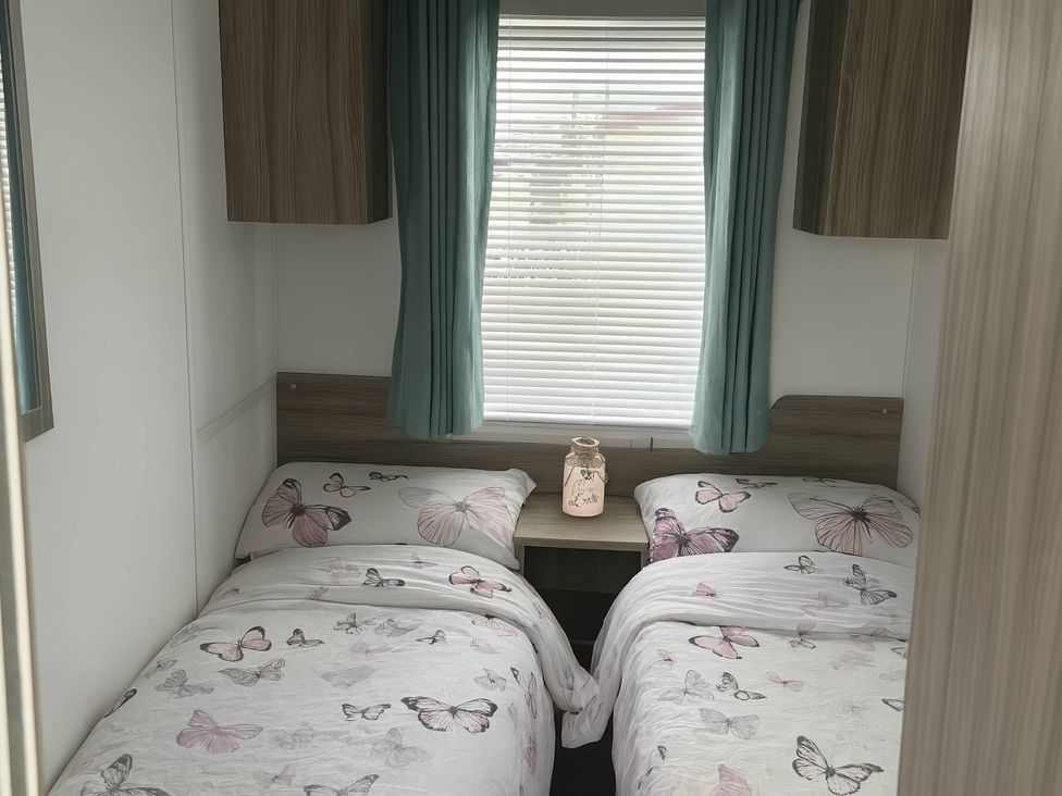 A bedroom with two beds and a bedside table at Whitehouse Leisure Park - Holiday Accommodation 19055, Towyn, Abergele
